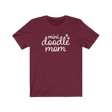 Load image into Gallery viewer, White script cute text that reads "mini doodle mom "with two paws on the right side on a burgundy T-shirt