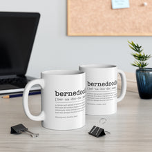 Load image into Gallery viewer, two bernedoodle dictionary definition mugs sitting on office desk with two paper clips on the table and a plant to the side with a cork board blurred in the background, along with a black laptop on the left side

