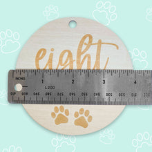 Load image into Gallery viewer, a silver ruler showing how big the puppy milestone is, which is 4 inches, on light teal background with white outlined paws scattered throughout the background
