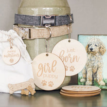 Load image into Gallery viewer, eautiful wooden lightweight circles with laser engraved lettering and paws that read my first groom and i learned fetch hanging from 2 dog collars (gray and khaki) with 3 small bones by burlap bag with portrait of goldnedoodle dog on block sign next to display
