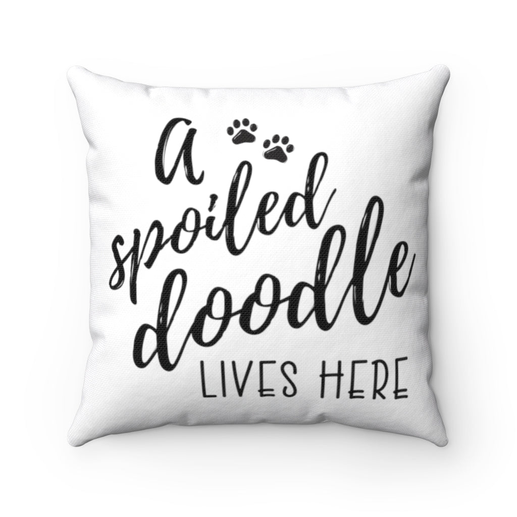 One white square throw pillow that reads A Spoiled Doodle Lives Here in black script font with two little paws