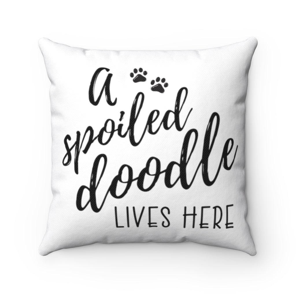 One white square throw pillow that reads A Spoiled Doodle Lives Here in black script font with two little paws