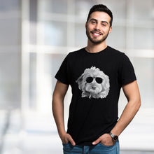 Load image into Gallery viewer, man with dark hair, beard and mustache wearing black t-shirt wtih black and white goldendoodle illustration. The dog is wearing black sunglasses. The guy has his hands in his pockets smiling at the camera. Blurred gray background.
