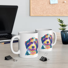 Load image into Gallery viewer, colorful Bernedoodle or Goldendoodle dog pop art illustration on two white ceramic mugs sitting on office desk with two paperclips in foreground and laptop in background with vase on right side and cork board on back wall
