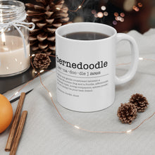 Load image into Gallery viewer, a white ceramic mug that includes black text in the format of a dictionary. It reads &quot;bernedoodle [ber•na•doo•dle] noun - a clever and gentle crossbreed between a Bernese Mountain Dog and a Poodle; affectionate; extremely loyal; loving companion; adores people; and will always be your best friend. Synonyms: doodle, dood sitting on a table cloth with fairy lights in the background, and three acorns surrounding the mug

