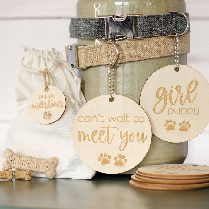 beautiful wooden lightweight circles with laser engraved lettering and paws that read my first groom and i learned fetch hanging from 2 dog collars (gray and khaki) with 3 small bones by burlap bag